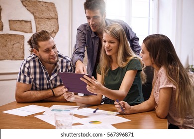 Professional Group Of Millenials In A Conference Room Looking And Pointing Excitedly At Tablet Pc That One Of The Ladies Is Holding Up For All