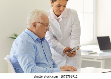 Professional guidance. Friendly nurse teaching senior patient to use healthcare phone app to set medicine reminders or track health indicators such as weight, blood glucose level, heart and pulse rate