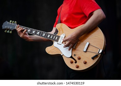 Professional Guitarist Man Playing Live Set On Stage With Electroacoustic Guitar In Hand.Guitar Player Performing Solo Part On Scene During Summer Music Festival Outdoor.Classic Rocker Plays Song