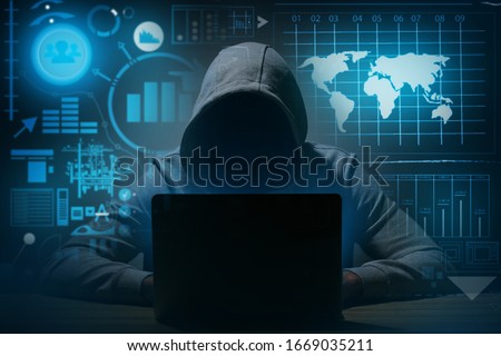 Professional hacker using laptop at table against dark background