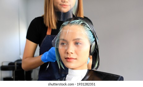 Professional Hair Dresser Coloring Beautiful Young Woman's Hair In Modern Beauty Salon. Beauty Salon Business Concept.