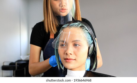 Professional Hair Dresser Coloring Beautiful Young Woman's Hair In Modern Beauty Salon. Beauty Salon Business Concept.