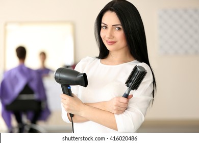 Professional hairdresser with comb and hairdryer