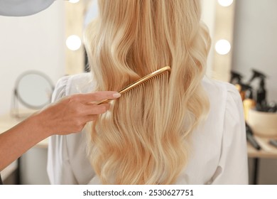 Professional hairdresser combing woman's hair in salon, closeup - Powered by Shutterstock