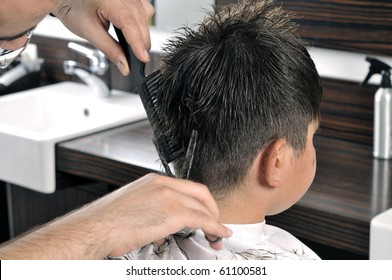 Professional hairdresser cutting childs hair in beauty saloon.
