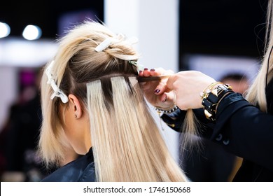 Professional hairdresser making hair extensions for blonde girl in a beauty salon - Shutterstock ID 1746150668