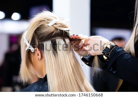 Professional hairdresser making hair extensions for blonde girl in a beauty salon Foto stock © 