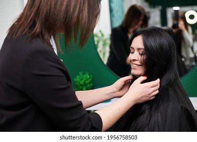 Professional Hairdresser Making Hairstyling For Female Client In Front Of Mirror. Close-up Picture Of Work Process In Barber Shop. Young Brunette Woman Getting Ready For Party