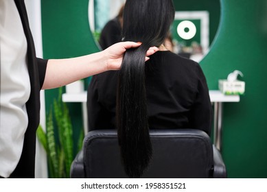 Professional Hairdresser Making Hairstyling For Female Client In Front Of Mirror. Close-up Picture Of Work Process In Barber Shop. Young Brunette Woman Getting Ready For Party