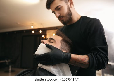 Professional Hairdresser Using Cold Towel To Calm Client's Skin After Shaving In Barbershop