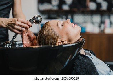 Professional hairdresser washing hair of a beautiful middle-aged woman in hair salon. - Powered by Shutterstock