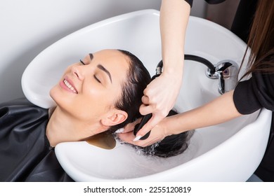 Professional hairdresser washing hair of young woman in beauty salon. Beautiful young woman with long black hair in a beauty salon. - Powered by Shutterstock