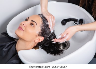 Professional hairdresser washing hair of young woman in beauty salon. Beautiful young woman with long black hair in a beauty salon. - Powered by Shutterstock