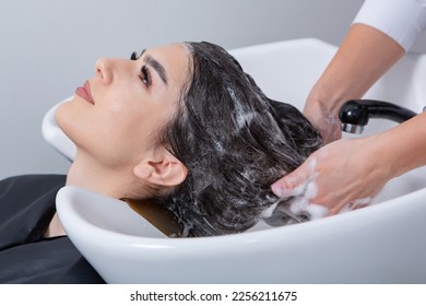 Professional hairdresser washing hair of young woman in beauty salon.The European brunette relaxes at the barber shop. - Powered by Shutterstock