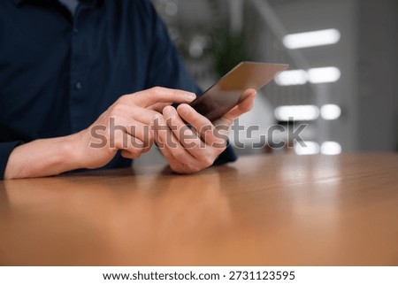 Professional hands holding and using a tablet at a desk, symbolizing technology, digital communication, online business, and modern workplace lifestyle.