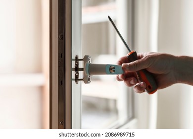 Professional handyman fixing window handle at home. Screwing the screw of window handle on pvc window. 