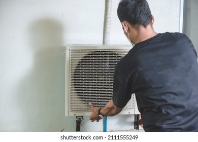 A Professional Handyman Opens Up The Front Hatch Of The Outside Compressor Unit Of Split Type Air Conditioner Unit. Repair Or Maintenance Work.