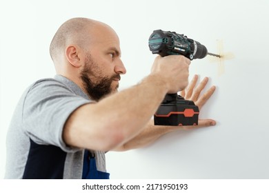 Professional handyman using a drill and drilling a hole in the wall - Shutterstock ID 2171950193