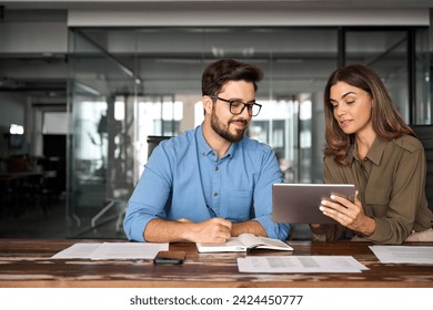 Professional happy manager showing work plan using tab helping employee. Busy colleagues working with digital tablet talking in office. Smiling professional partners having conversation at meeting. - Powered by Shutterstock