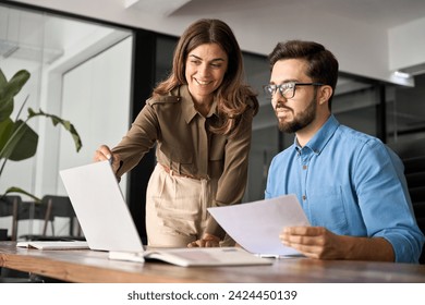 Professional happy middle aged business woman manager explaining corporate software elearning webinar helping young employee at work looking at computer. Busy colleagues using laptop talking in office - Powered by Shutterstock