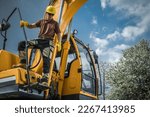 Professional Heavy Duty Machinery Operator Standing on Excavator Machine. Construction Industry Theme.