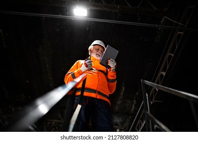 Professional heavy industry engineer worker wearing safety uniform and hard hat, using tablet computer controlling production.
