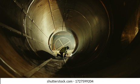Professional Heavy Industry Worker Wearing Helmet Welding Inside Oil and Gas Pipe. Construction of the Oil, Natural Gas and Biofuels Transport Pipeline. Industrial Manufacturing Factory