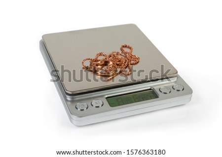 Professional high precision digital table top scales with LCD display and gold jewelry on them on a white background, close-up in selective focus
