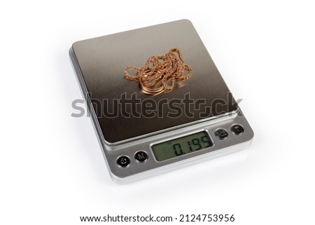 Professional high precision digital table top scales with LCD display and weighable gold jewelry on them on a white background
