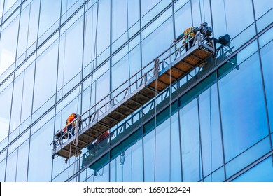 Professional high rise window cleaning service workers in gondola. Two workers use specialized equipment to access and clean windows of skyscraper as preventative maintenance and repair measure.. - Powered by Shutterstock