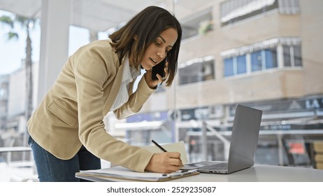 A professional hispanic woman multitasks with a phone call and notetaking in a corporate environment, exuding confidence and poise. - Powered by Shutterstock