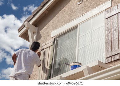 Professional House Painter Painting the Trim And Shutters of A Home.