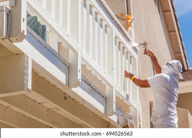 Professional House Painter Wearing Facial Protection Spray Painting Deck Of A Home.