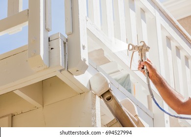 Professional House Painter Wearing Facial Protection Spray Painting Deck Of A Home.