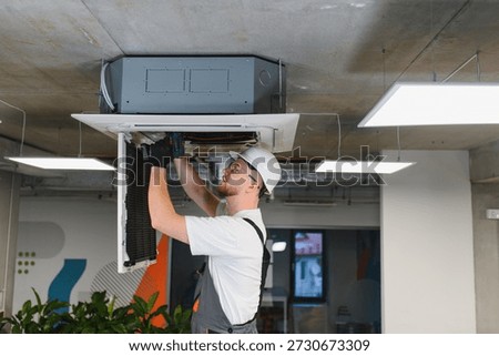 Professional hvac engineer installing and maintaining a ventilation unit on the office ceiling, ensuring proper climate control