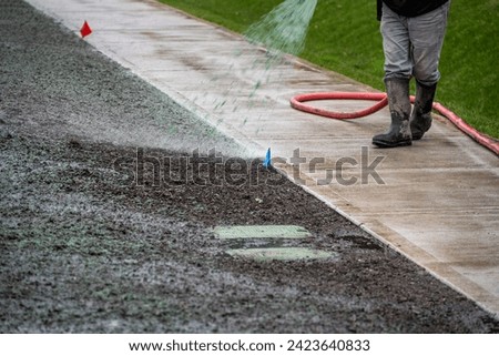 Professional hydroseeding, workman spraying a mix of grass seed and wood pulp from a big hose onto a freshly prepared dirt in a new residential community
 Foto d'archivio © 