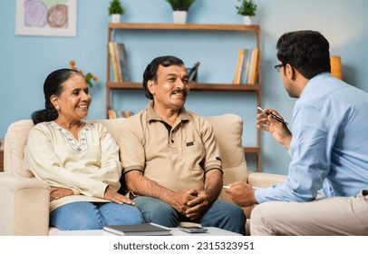 Professional Indian banker explaining about insurance policy to senior couple at home - concept of financial advisor, business expert and banking support