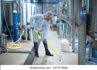 Professional Industrial Cleaner In Protective Uniform Cleaning Floor Of Food Processing Plant. Cleaning Services.