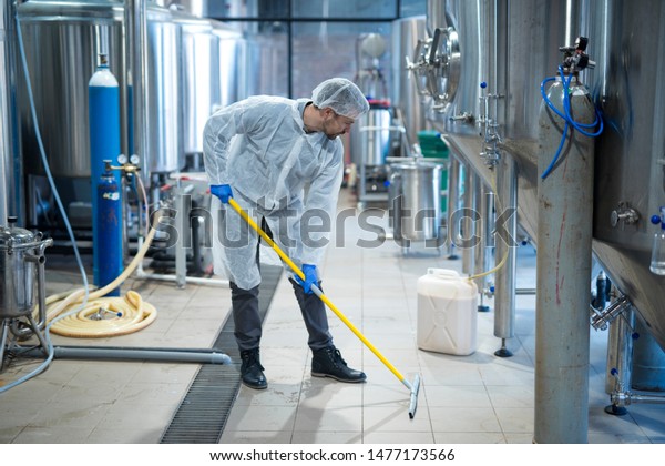 Professional\
industrial cleaner in protective uniform cleaning floor of food\
processing plant. Cleaning\
services.