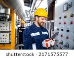 Professional industrial electrician in safety work wear checking power consumption on tablet computer.