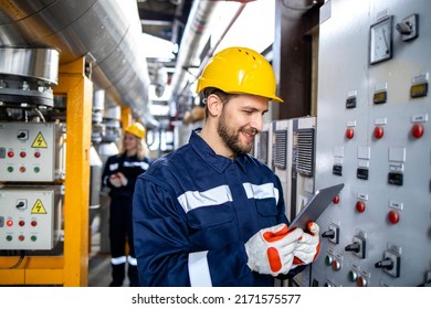 Professional industrial electrician in safety work wear checking power consumption on tablet computer. - Shutterstock ID 2171575577