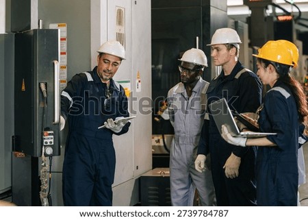 Professional instructor senior engineer man training young engineer team to control operate CNC metal milling machine in heavy industry factory