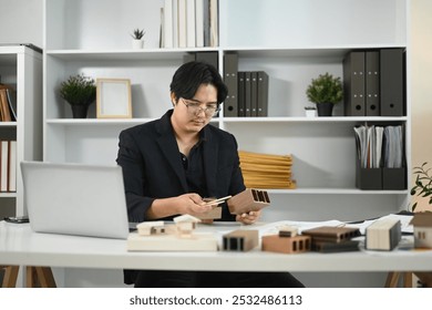 Professional interior designer examines various material samples in a modern workspace - Powered by Shutterstock