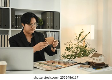 Professional interior designer examines various material samples in a modern workspace - Powered by Shutterstock