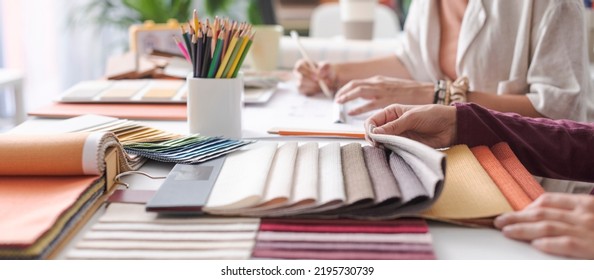 Professional interior designers working together on a project in their office: they are checking fabric swatches and picking the right color palette, hands close up - Powered by Shutterstock