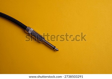 Professional Jack Audio Cables Placed Horizontally Against a Vibrant Yellow Textured Background