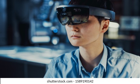 Professional Japanese Electronics Development Engineer in Blue Shirt is Wearing a Virtual Reality Headset and Looking Around the High Tech Research Laboratory with Modern Computer Equipment.