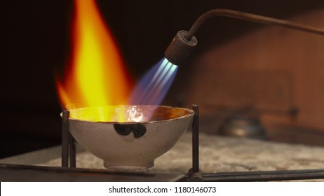 Professional jeweler using gas torch for melting precious metal. Close up of handlers tilting crucible to the sides. Jewelry specialist directing the flame right on the sterling silver - Powered by Shutterstock