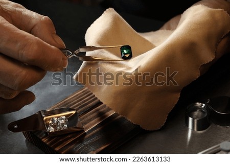 Professional jeweler working with gemstone at table, closeup