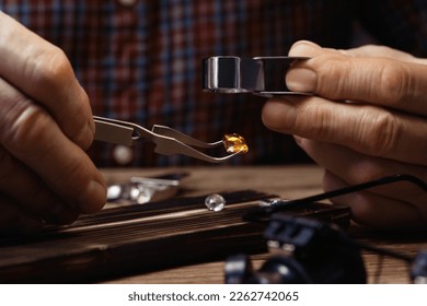 Professional jeweler working with gemstone at wooden table, closeup - Shutterstock ID 2262742065